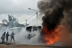 Ivorian fire fighters try to extinguish a burning bus in Yopougon district of Abidjan on September 10, 2015.  By Issouf Sanogo AFP