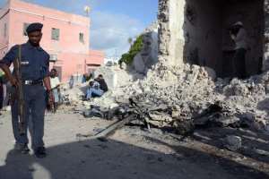 A Somali policeman walks past the remains of a car bomb outside Mogadishu's City Palace Hotel on May 31, 2014.  By Mohamed Abdiwahab AFP