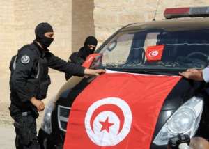 Tunisian Police Special Unit agents fix a national flag on their vehicle in the central city of Kairouan on May 19, 2013.  By Fethi Belaid (AFP)