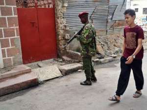 A young resident walks past an armed police officer on July 6, 2014 at the scene of an attack on three Russian nationals while they were touring Mombasa's old-town district.  By  AFPFile