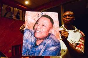 A man holds a picture of late Congolese singer King Kester Emeneya in the bar Toison d'or Golden Fleece in the Bandal neighbourhood of Kinshasa on February 13, 2014.  By Junior D. Kannah AFP