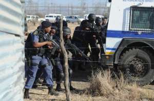 Police officers ready their weapons as miners protest near a platinum mine in Marikana on August 16, 2012.  By  AFPFile