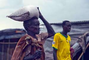 This photo taken on July 9, 2014 shows an internally displaced South Sudanese elderly woman carrying a bag of relief food to her makeshift shelter at an IDP camp a in Malakal.  By Ali Ngethi AFPFile