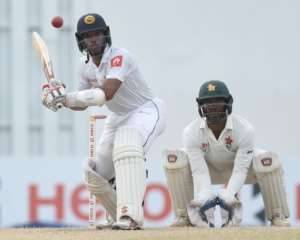Sri Lankan batsman Kusal Mendis left plays a shot as Zimbabwe wicketkeeper Regis Chakabva looks on during the fourth day of a one-off Test match at the R Premadasa stadium in Colombo on July 17, 2017.  By ISHARA S. KODIKARA AFP