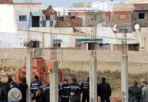 Tunisian special forces stand outside a bullet-riddled building in the Tunis suburb of Raoued on February 4, 2014.  By  (AFP)