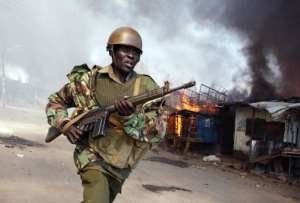 A Kenyan policeman runs past burning houses in Nairobi.  By Boniface Mwangi (AFP/File)
