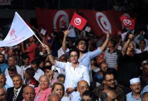 People wave Tunisian and Nidaa Tounes Call for Tunisia party flags at an election campaign meeting ahead of the parliamentary vote on October 9, 2014 in the Mellassine district, a  suburb of Tunis.  By Fethi Belaid AFPFile