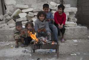 Syrian children heat themselves by a fire in the rebel-held Tal Zarzour neighbourhood of Aleppo on November 23, 2014.  By Baraa al-Halabi AFPFile
