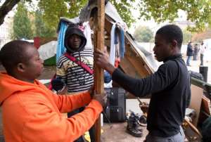 Ghanaian refugee Johnson Takyi R builds a makeshift shelter with fellow Ghanians in an improvised refugee camp on Oranienplatz square in Berlin's Kreuzberg district, on October 16, 2013.  By John Macdougall AFPFile