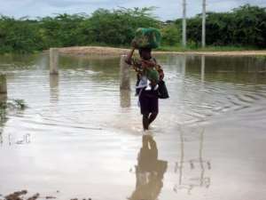 A woman, carrying a baby, wades through a flooded street in the outskirts of Chokwe, southern Mozambique.  By Johannes Myburgh AFPFile