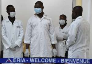 Medical staff wearing protective masks wait for passengers arriving from Conakry in Guinea at Abidjan airport on October 20, 2014 as Ivory Coast's airline resumed flights to the three west African countries worst-hit by Ebola.  By Issouf Sanogo AFP
