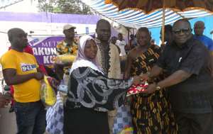 Afrifa Yamoah Ponkoh presenting a piece of cloth to a widow as the Krapahene and PJ Mozey look on