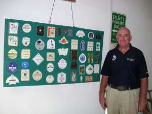 Richard White in a pose on a hoisted tags of the 50 out of 100 golf courses he has played.