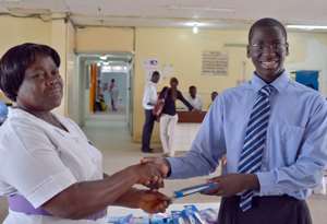 Joel Bervell presenting a thermometer to Mrs. Rebecca Lartey at the Korle Bu Children's Hospital.