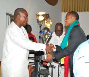 Dede Ayew presents the World Youth Cup trophy to Vice President John Mahama