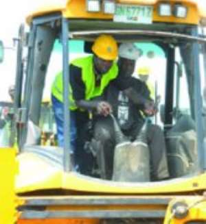 Vice-President  John  Mahama  using  an  excavator  to  cut  the  sod  for  commencement of work on the BRT project on the Graphic Road in Accra.