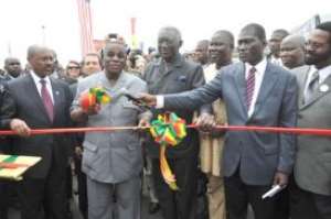 President Atta Mills (2nd left) being assisted by former President  John Kufuor (3rd left) to cut the tape to inaugurate the road