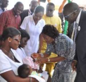 First Lady Naadu Mills administering the first dose of the new vaccines to one of the children during the Africa Vaccination Week celebration in Accra