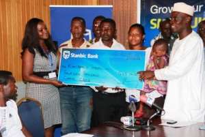 Minister of Trade and Industry, Haruna Iddrisu, presents the dummy cheque of GHC14,000 to the affected Kantamanto traders on behalf of Stanbic Bank