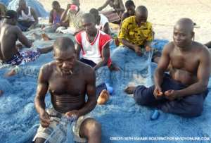 Fishermen mending their nets at Efasu in the Western Region