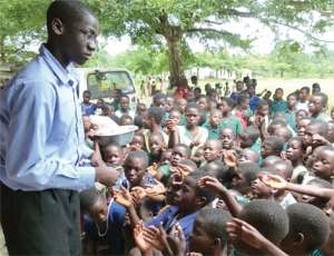 Joel looks sympathetic as the children struggle for the pencils he wants to give to them