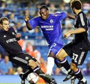 Michael Essien (in blue jersey) controls a ball between two opponents