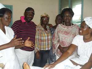 A nurse (far left) explaining a point to the visitors. Seated on the bed (right) is the patient