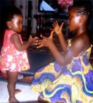 A one-year-old baby learning from her elder sister.