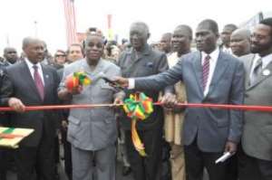 President Atta Mills 2nd left being assisted by former President  John Kufuor 3rd left to cut the tape to inaugurate the road