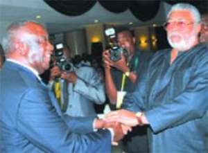 President Gbagbo in a handshake with Former President Rawlings at the Banquet Hall during the luncheon.