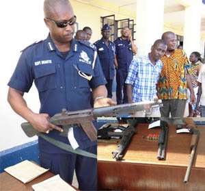 DCOP Kofi Baokye examing one of the robbers8217; weapons. INSET: The weapons and ammunitions