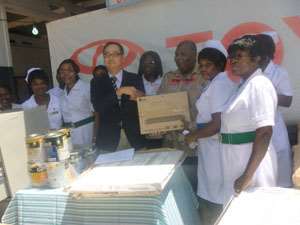 Takahiko Takabayashi (left) presenting the items to Mawutowu Kwesi Brese (right) with health officials.