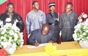 Mr Kenneth Ashigbey, MD of Graphic Communications  Group Limited (GCGL),signing tne Book of Condolence. Standing behind him are officials of GCGL and a policewoman on duty