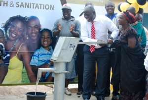 Nana Narkie Yomo III is assisted to pump water out of the commissioned borehole.