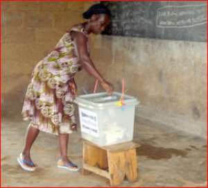 A woman casting her ballot in a classroom