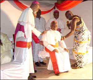 Cardinal Turkson being supported to sit on the stool