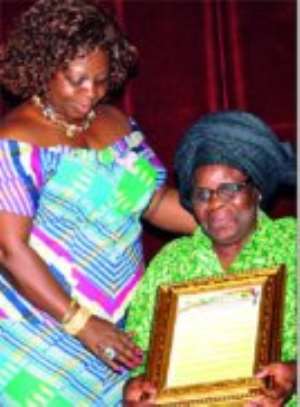 Professor Ama Ata Aidoo (seated), receiving her award from Mrs Juliana Azuma-Mensah, Minister of Women and Childrens Affairs, in the category of Culture and Literature.
