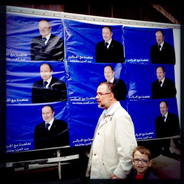 A man walks past posters of Algerian president Abdelaziz Bouteflika in Algiers on April 15, 2014. By Patrick Baz (AFP)