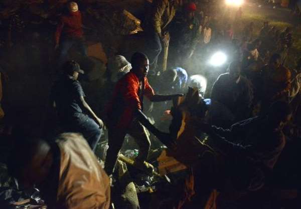 Civilian volunteers help carry away debris from the scene of a collapsed residential building in Nairobi on January 4, 2015. By Tony Karumba (AFP)