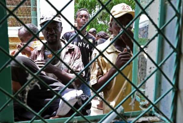 Kenyans cover their noses as they look through a metal window grate at the mortuary in the northeastern town of Garissa, on April 4, 2015. By Carl De Souza (AFP)