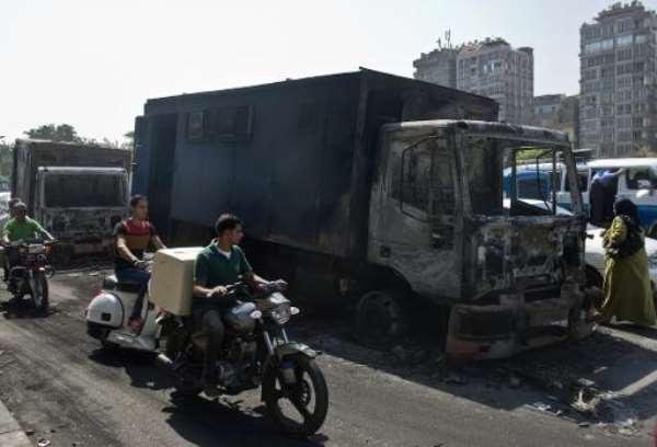 Egyptians ride past by a burnt-out police vehicle which was set on fire by Muslim Brotherhood supporters during clashes in Cairo, on October 7, 2013. By Khaled Desouki (AFP)