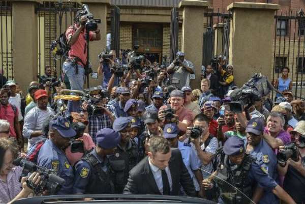 South African Paralympic athlete Oscar Pistorius (Front), surrounded by policemen, journalists and onlookers, leaves the Pretoria Hight Court following his sentencing hearing on October 13, 2014. By Mujahid Safodien (AFP)