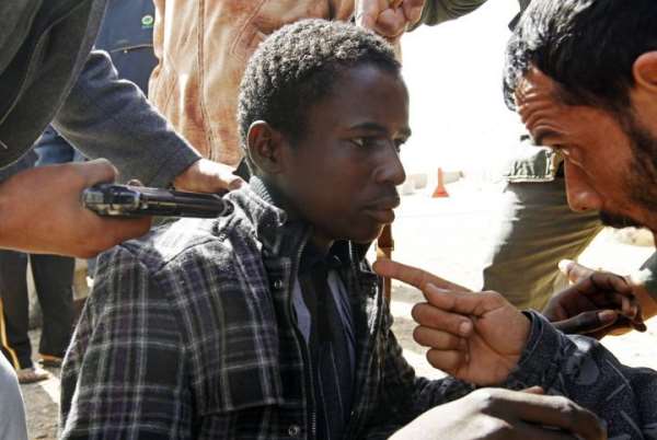 Rebels hold a young man at gunpoint, who they accuse of being a loyalist to Libyan leader Muammar Gaddafi, between the towns of Brega and Ras Lanuf, March 3, 2011. REUTERS/Goran Tomasevic
