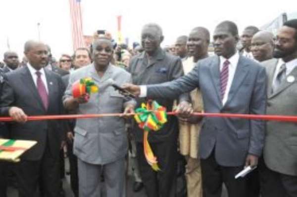 President Atta Mills (2nd left) being assisted by former President John Kufuor (3rd left) to cut the tape to inaugurate the road