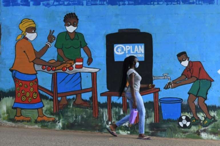 A woman with a face mask walks past graffiti that promotes hand washing and wearing face masks in Nairobi.  By Simon MAINA (AFP/File)