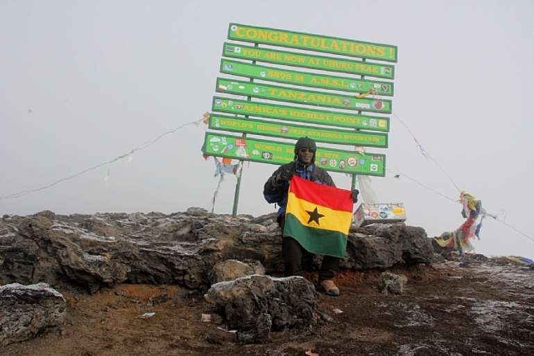 Elated: Muntaka Chasant celebrates with a Ghana flag as he sits on the summit of the Mount Kilimanjaro