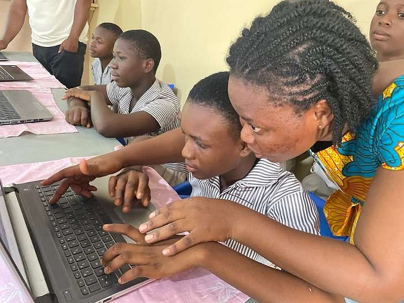 Sylvia Akpih, the manager of the Impact Hub Academy, guiding some of her pupils on how to use the Internet after the installation of the Starlink device at her school.