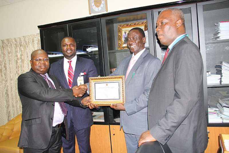 Mr. John Kofi Mensah (1st Left), CEO Of First Capital Plus Bank Receiving The Universal Banking License From Mr. Franklin Belnye (2nd Left), Director/Head, Banking Supervision Dept. Bank Of Ghana (BoG). Looking On Is William Ato Essien (2nd Left), Board Member Of First Capital Plus Bank And Mr. Raymond Amanfu (Far Right), Head Of Other Financial Institutions Dept (BoG)