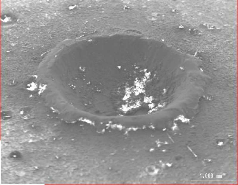 Looking somewhat like Meteor Crater from the air, this is actually an SEI of one ofthe meteoroid impact craters on the surface of the helium tank.