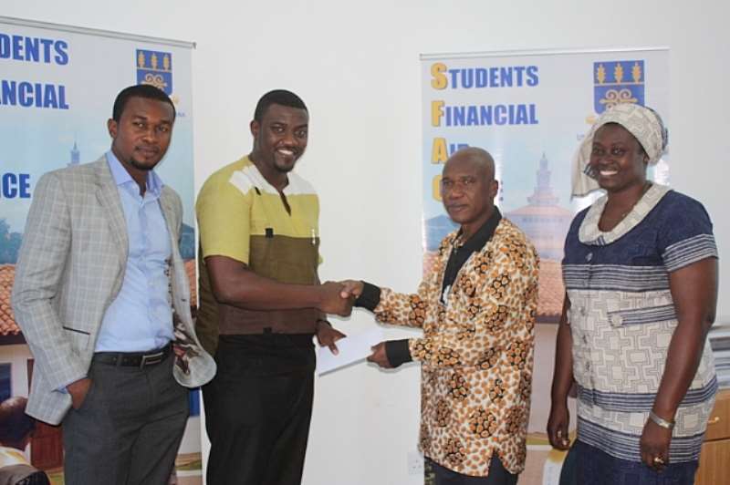 JOHN DUMELO PRESENTING THE CHEQUE TO DR. JAMES K. ADOMAKO, DEAN OF STUDENT AFFAIRS